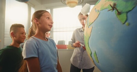 STEM Science Lesson: Smart School Girl Presenting Renewable Energy Sources Using Globe with 3D Models of Wind Turbines and Solar Panels. Primary School Children Studying Ecology with Female Teacher. - Powered by Adobe