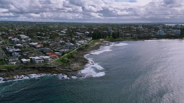 Cronulla, Sydney, Australia&ndash;UHD Drone Video- Spectacular nature and cityscape, flying over the surf along the Cronulla Beach rocky shoreline, with an impressive rain cloud forming in the background.