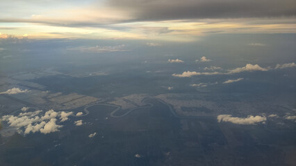 This image shows a beautiful view from above the clouds, taken from an airplane window. Fluffy...