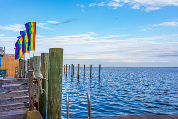 Pride flags in a dock with sea view and blue sky in Fire Island, New York.