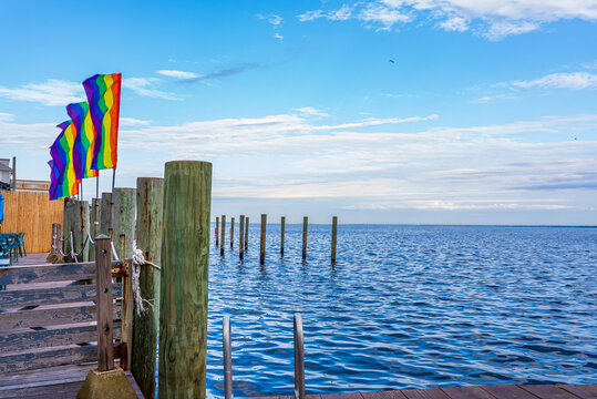 Pride flags in a dock with sea view and blue sky in Fire Island, New York.