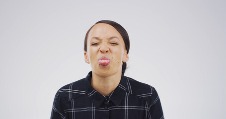 Girl, funny face and tongue out in studio with joke, playful and mock up space on white background....