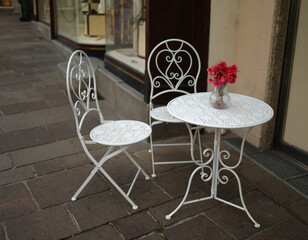 A table with chairs on the street near a restaurant