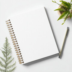 White spiral notebook with pen and green fern leaves