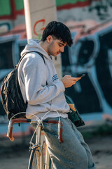 young man on the street with mobile phone leaning on vintage bicycle
