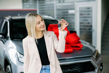 Happy business woman showing car key in dealership