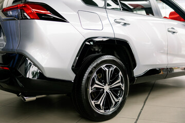 Close-up of alloy wheel and exhaust pipe of modern car parked in showroom