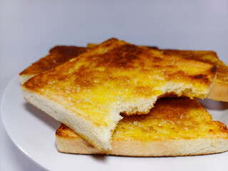 Several slices of golden-brown buttered toast sprinkled with sugar. One slice in the foreground...