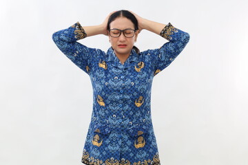 Stressed Indonesian civil servant woman standing while holding her head