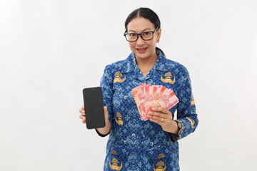 Attractive young asian civil servant holding Indonesia banknotes while showing blank cell phone...