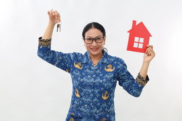 Female hand holding small paper house and keys , posing over white color background wall in studio...