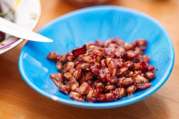 Freshly extracted cherry pits arranged in a blue ceramic bowl, showcasing fruit preparation remnants
