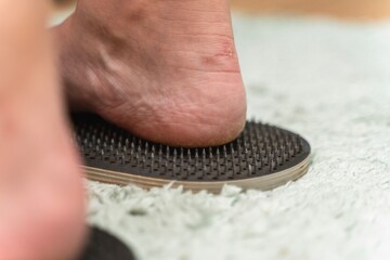 Person standing on a Sadhu nail board, showing a heel's-eye view of the sharp spikes piercing the...