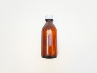 Amber glass bottle with an aluminum cap laying isolated on a white background, brown glass bottle for pharmaceuticals, syrups, essential oils, and cosmetics