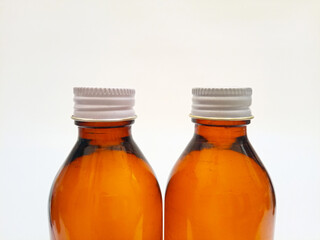 Amber glass bottles with aluminum caps on a white background, closeup, brown glass bottle for pharmaceuticals, syrups, essential oils, and cosmetics