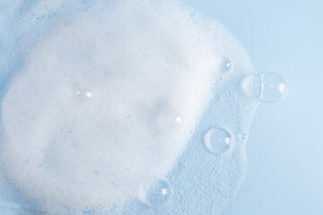 Chic white fluffy foam, soap foam texture with clear bubbles on blue background. A copy space....