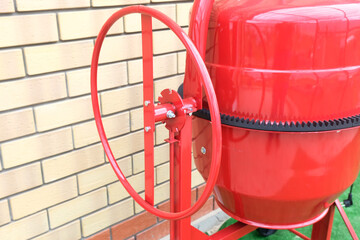 New red concrete mixer, type of tipping mechanism. Construction tool for preparing concrete mix.