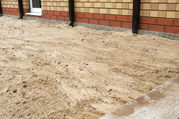 Preparing the base for pouring the concrete slab. Filling the construction site with sand.