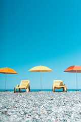 Colorful Beach Umbrellas and Sun Loungers on a Pebble Seaside