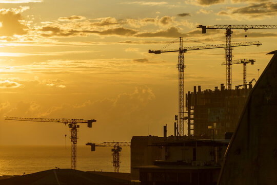 Construction Cranes at Sunset. Building the Future - Powered by Adobe