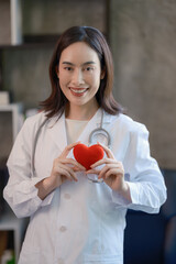 Asian female doctor holding a red heart in her hands in the concept of care your heart.