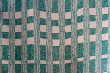 Textile woolen thin bedspread with square patterns of white and dark green with longitudinal stripes