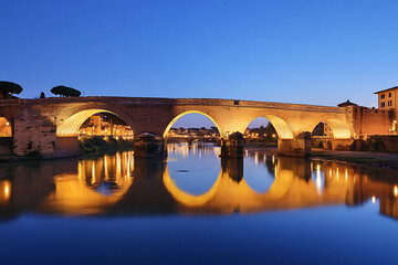 A historic European bridge illuminated at dusk its arches reflected in a calm river under a star speckled sky