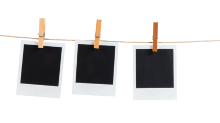 Three blank black polaroids hanging on wooden clothespins on a string isolated on transparent background