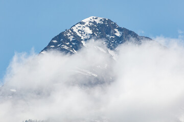 A mountain covered in snow and clouds