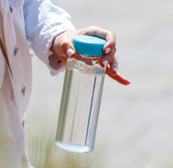 A person is holding a clear bottle with a blue lid
