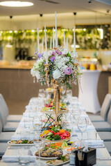 A long dining table adorned with gourmet dishes, elegant glassware, and a floral centerpiece