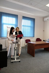 Two business women work in the office to solve problems and sign agreements.