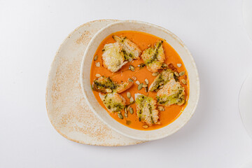 A vibrant dish showcases ravioli in rich roasted tomato sauce, topped with crunchy pumpkin seeds