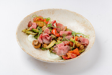 A vibrant salad with roasted veggies, tasty meats, and rich dressing entices all!