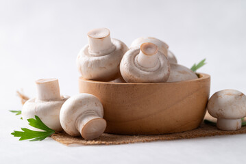 White Button mushroom or Champignon mushroom (Agaricus bisporus) in wooden bowl on white background, Food ingredient