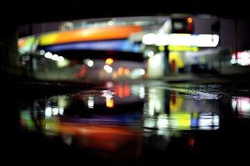 Nighttime urban scene reflected in a puddle.  Blurred lights of a bridge and roadway below