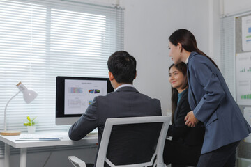 Professionals in a modern office analyzing data on a computer screen, engaging in collaborative...