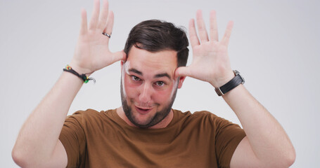 Silly man, portrait and funny face with hands in studio for antlers or ears on a white background....