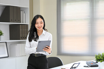 Cheerful office worker browsing content or managing tasks on a digital tablet