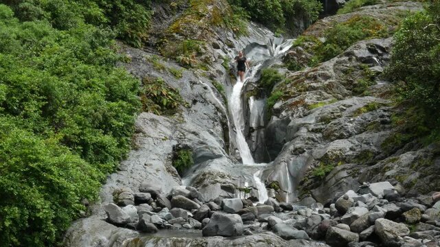 hiker intentionally slides down water fall in forest