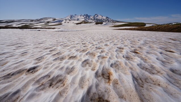 Melting Snow Landscape Revealing Earth Leading to Snowy Mountain Range Under Clear Blue Sky