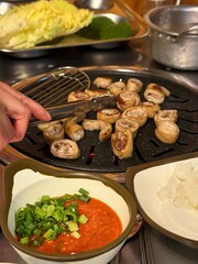 Grilled makchang, Korean beef or pork intestine, cooked to crispy perfection with a smoky, chewy texture. Served with dipping sauces and vegetables for a flavorful and savory experience.