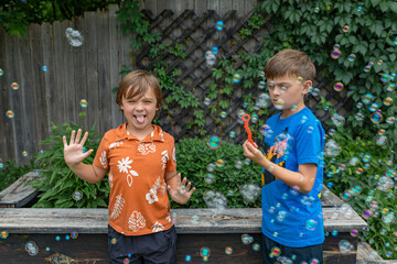 Two boys  one with tongue out playing with bubbles