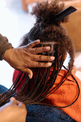 Young mixed race girl having her hair braided
