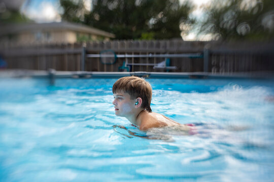 Boy swimming in backyard pool on a sunny summer day