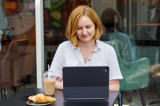 Cheerful woman working on laptop at a caffe