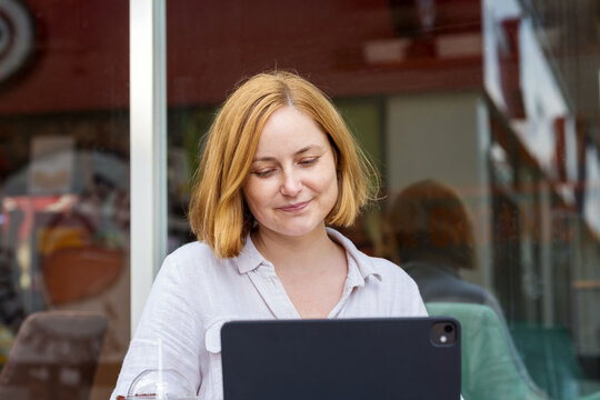Cheerful woman working on laptop at a caffe