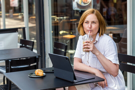 Middle age woman drinking coffee and working on laptop at a caffe