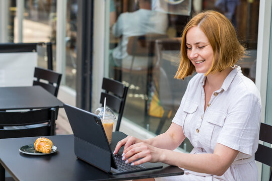 Woman working on laptop, sitting in a modern cafe