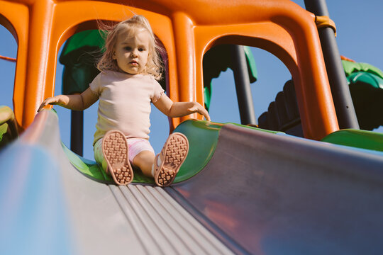Caucasian toddler slides down playground slide
